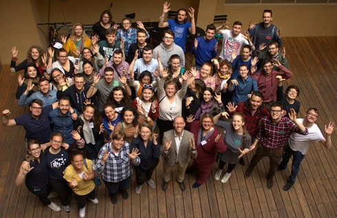 Foto scattata dall'alto, Humberto si trova davanti a una centinaia di studenti universitari e laureati, tutti con le mani alzate in segno di applauso tipico delle persone sorde.