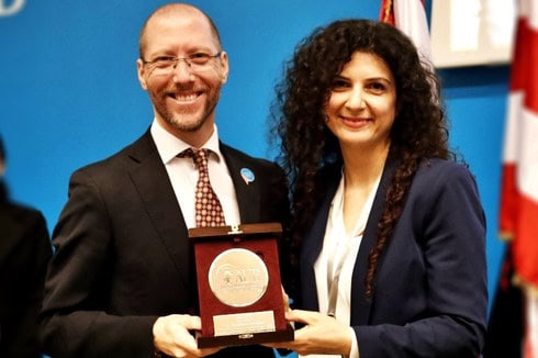 Humberto sta sorridendo insieme al responsabile dell'evento, il quale gli sta consegnando il premio