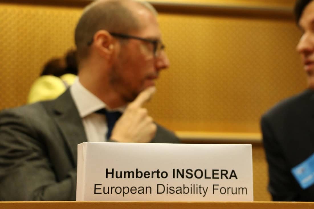 Humberto è seduto e sta parlando con una persona. Di fronte a lui, c'è un pannello con la scritta 'Humberto Insolera - European Disability Forum’